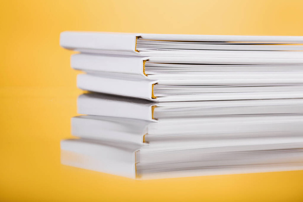 Stack of White Books on yellow  Background. Close up photobook stacked. forefront of a group of books stacked. An abstract shot of a pile of books. Blank white stack of books. - Photo, Image
