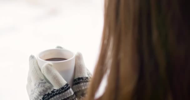 Egy meleg kesztyűs nő forró csokoládéval, teával vagy kávéval teli fehér csészét tart télen a szabadban. Kiváló minőségű 4k felvételek - Felvétel, videó