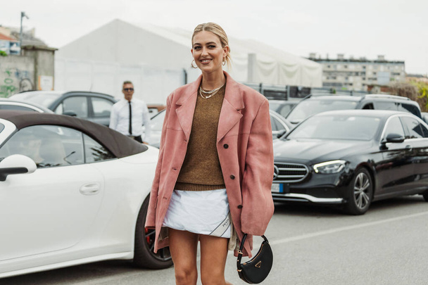 Эмили Синдлв носит ожерелья, вязаный свитер, розовую замшевую куртку, сумку Prada, которую видели на выставке PRADA во время Миланской недели моды Женская одежда Весна / Лето 2024. - Фото, изображение