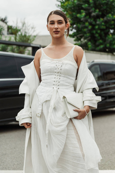 Un invitado lleva vestido blanco, abrigo y bolso, visto fuera del espectáculo PRADA durante la Semana de la Moda de Milán Womenswear Primavera / Verano 2024. - Foto, imagen