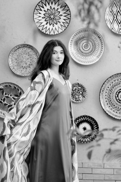 Mulher bonita, modelo, menina em vestido de moda do Uzbequistão popular nacional com padrão ikat. Tashkent, Uzbequistão. Preto e branco - Foto, Imagem
