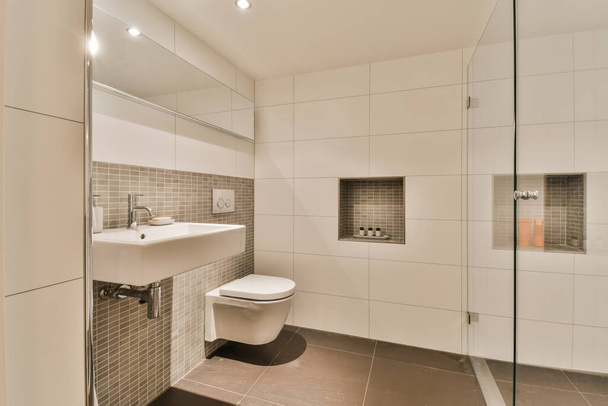 ванная комната с туалетом, раковиной и душевой кабиной в той же комнате с левой стороны фотографии - Фото, изображение