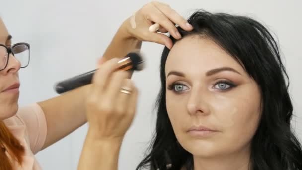Schöne junge Frau macht stilvolle Abend Make-up von professionellen Maskenbildner im Schönheitsstudio. - Filmmaterial, Video