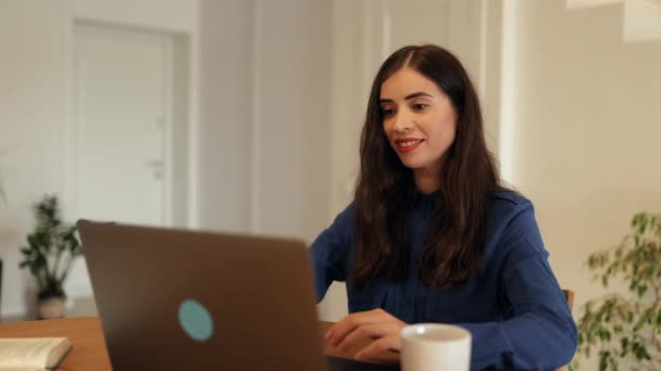 Mladá žena pracuje doma v obývacím pokoji u stolu na notebooku, dálkovém vzdělávání nebo v práci - Záběry, video