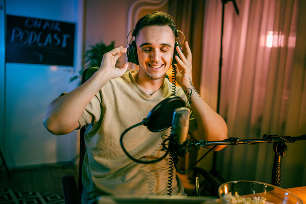 One man caucasian male blogger or vlogger gesticulating while streaming video podcast in broadcasting studio use microphone and headphones famous influencer shooting video for channel podcast - Φωτογραφία, εικόνα