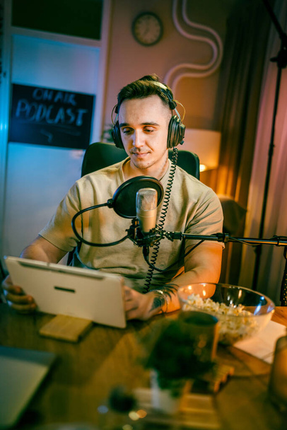 One man caucasian male blogger or vlogger gesticulating while streaming video podcast in broadcasting studio use microphone and headphones famous influencer shooting video for channel podcast - Foto, imagen