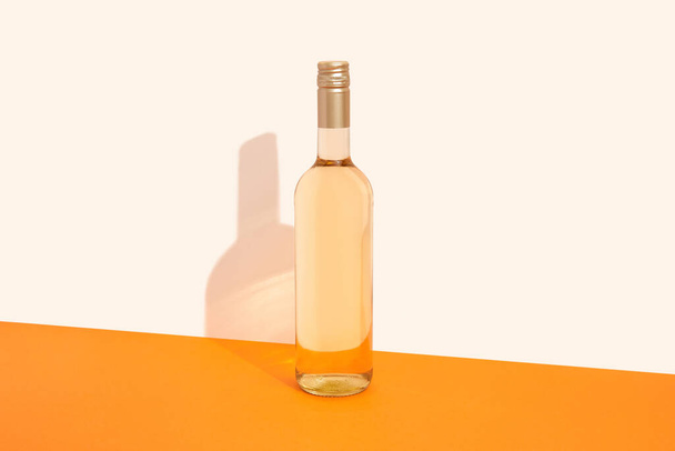 Бутылка белого вина на оранжевом фоне с глубокими тенями. Придумайте напиток с местом для вас lable и смс. Дизайн упаковки продукта. - Фото, изображение