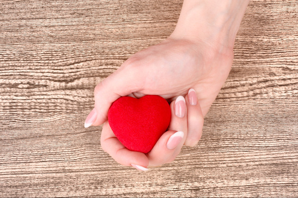 coração vermelho nas mãos sobre fundo de madeira
 - Foto, Imagem