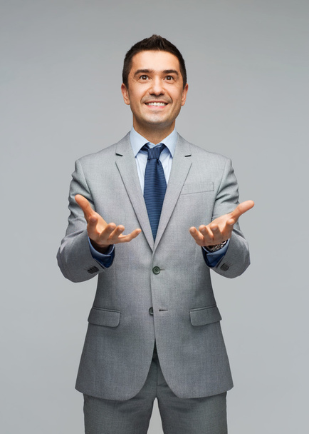 happy businessman in suit showing empty palms - Foto, afbeelding