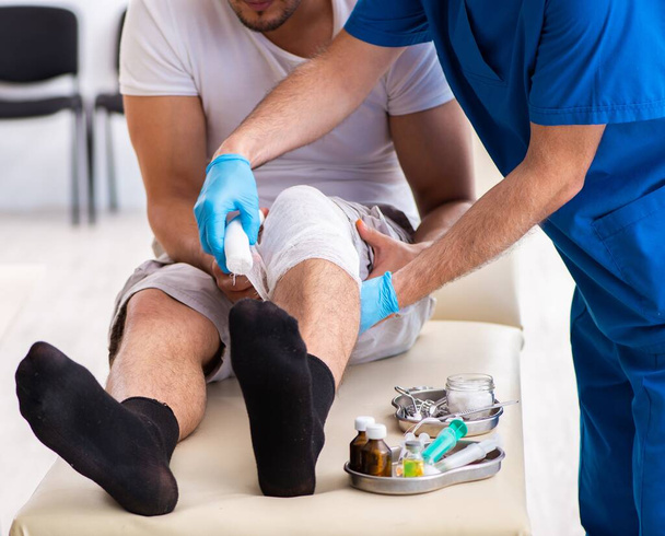 Раненый на ноге врач в концепции оказания первой медицинской помощи
 - Фото, изображение