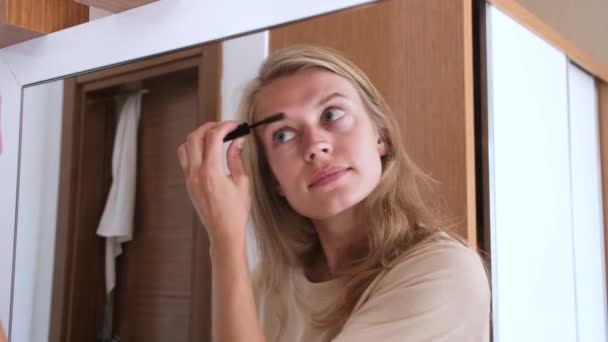 Kaunis nainen muodostavat peilin hotellihuoneessa, harjaamalla kulmakarvat - Materiaali, video