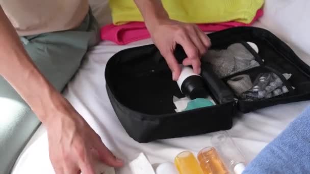 Cestovní kosmetická souprava s láhvemi, pilulkami a kosmetikou na posteli, pohled shora - Záběry, video