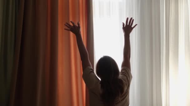 Молодая женщина просыпается и растягивается утром в гостиничном номере, вид сзади - Кадры, видео