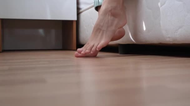 Morgens aufstehen. Blick auf weibliche Füße, die nach dem Aufwachen auf dem Boden stehen - Filmmaterial, Video