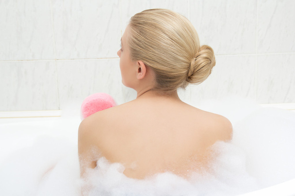 Vista posterior de la mujer de relajarse en el baño y se lava a sí misma - Foto, imagen