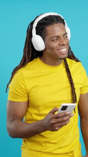 Uomo latino con dreadlocks che ascolta musica con gli occhi chiusi in studio con sfondo blu - Filmati, video