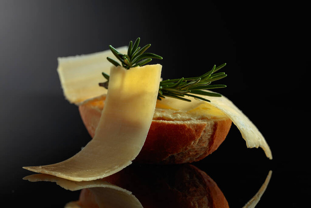 Sandwich with Parmesan cheese and rosemary on a black reflective background. - Foto, Imagem
