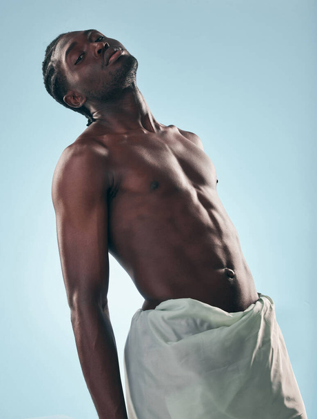Cuerpo, hombre negro y retrato en estudio con arte, cuidado de la piel y resplandor de bienestar y confianza. Músculo fuerte y modelo masculino africano con fondo azul creativo y relajarse con potencia y fitness. - Foto, imagen