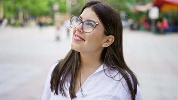 Giovane bella donna ispanica con gli occhiali sorridente felice per le strade di Madrid - Filmati, video