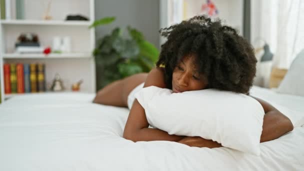 Αφροαμερικανή που αγκαλιάζει μαξιλάρι ξαπλωμένη στο κρεβάτι και δείχνει σέξι στο υπνοδωμάτιο. - Πλάνα, βίντεο