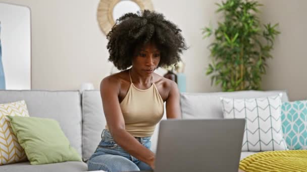 Afroamerikanerin sitzt gestresst mit Laptop zu Hause auf Sofa - Filmmaterial, Video