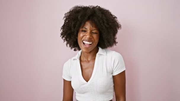 Afrykańska amerykanka uśmiecha się pewnie robiąc znak ok z kciukiem do góry nad odizolowanym różowym tle - Materiał filmowy, wideo