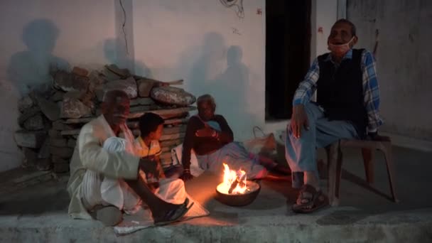 KHAJURAHO, MADHYA PRADESH, ÍNDIA, 05 DE MARÇO DE 2022: Grupo de pessoas rurais sentadas e relaxantes perto da fogueira.  - Filmagem, Vídeo