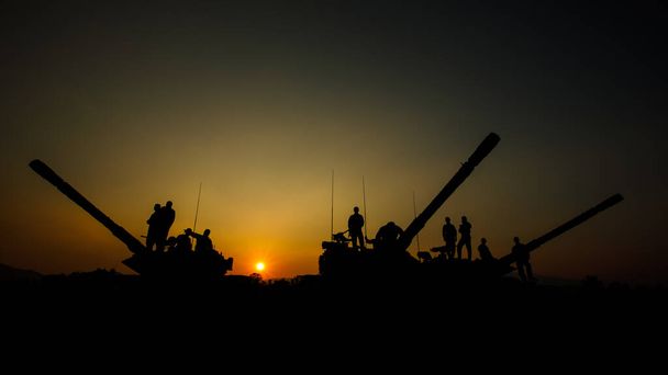 silhouette gruppo di forze speciali sodiers in piedi e sedersi su camion cannone serbatoio con sopra lo sfondo del tramonto, squadre speciali di addestramento operazioni di guerra - Foto, immagini
