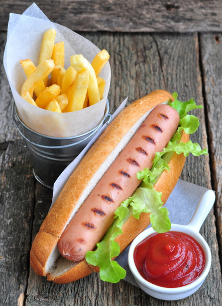 Hot dog avec laitue fraîche et frites sur une table en bois
 - Photo, image