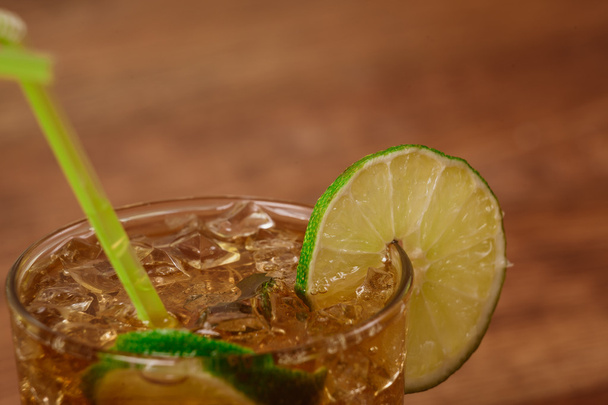 drink concept - cocktail with cola ice cubes and lime - Foto, afbeelding