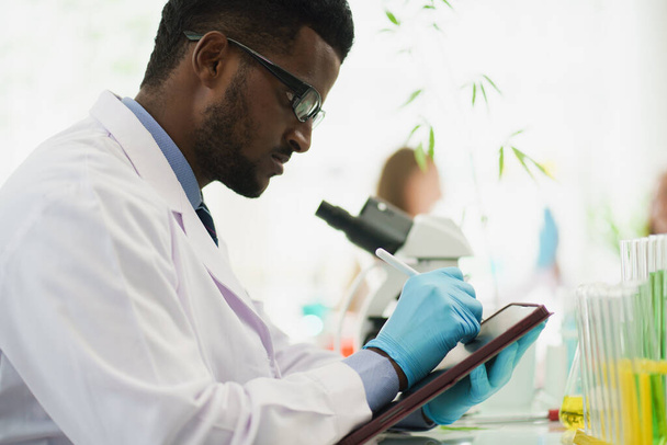 Scientist or biology researcher working in the lab with tablet and microscope in the background. - Photo, Image