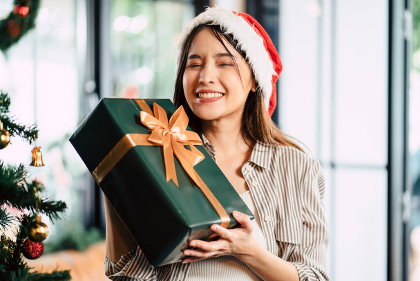 Asiatische schöne Frau, die mit Geschenkbox in der Weihnachtszeit glücklich ist. - Foto, Bild