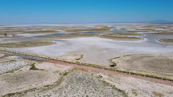 Drone uitzicht op auto bewegen langs de weg op dood zout meer Tuz in Turkije. Landschap is als op Maan of Mars, alles gedroogd bedekt met zout. Hier eetbaar zout gewonnen en verwerkt in fabriek of fabriek. - Video