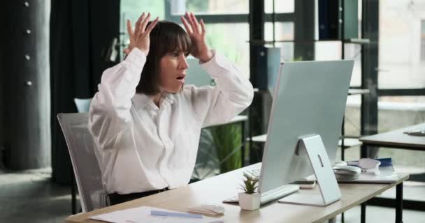 Ümitsiz iş kadını ofisteki bilgisayar masasında oturuyor, ifadesi hayal kırıklığını ya da üzüntüyü yansıtıyor. Zorluklara göğüs gererek direncini gösteriyor.. - Video, Çekim