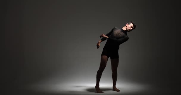 Een man levert een boeiende hedendaagse dansvoorstelling tegen een subtiele grijze achtergrond. Zijn expressieve en vloeiende bewegingen creëren een visueel boeiende en artistieke ervaring. - Video