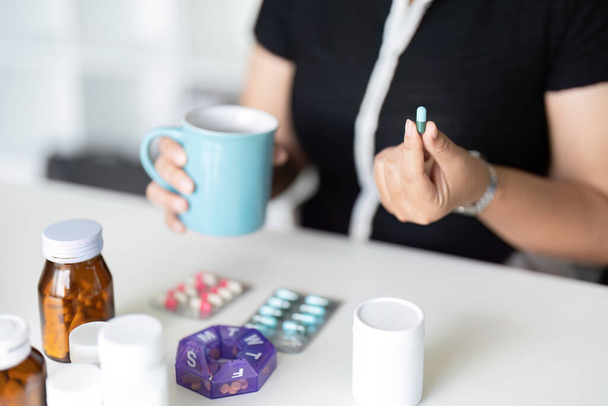 Больная женщина держит таблетку на руке наливая капсулы и стекло принимать обезболивающие добавки лекарства. Здравоохранение, головная боль, лечение, концепция терапии. - Фото, изображение