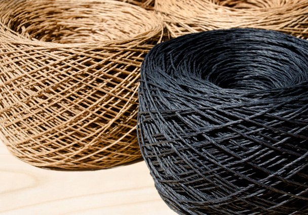 ECO material. Close-up of raffia balls on a wooden board. Skeins of black and beige raffia are ready to be knitted. - Photo, Image