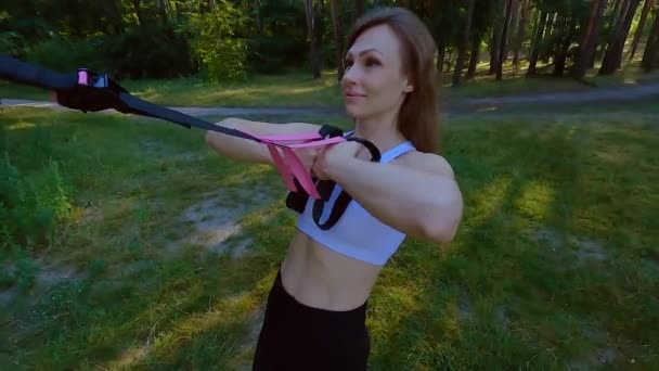 Une femme est engagée dans un simulateur de caoutchouc sportif étirant une bande élastique. Bandes de caoutchouc pour l'entraînement musculaire sportif. - Séquence, vidéo