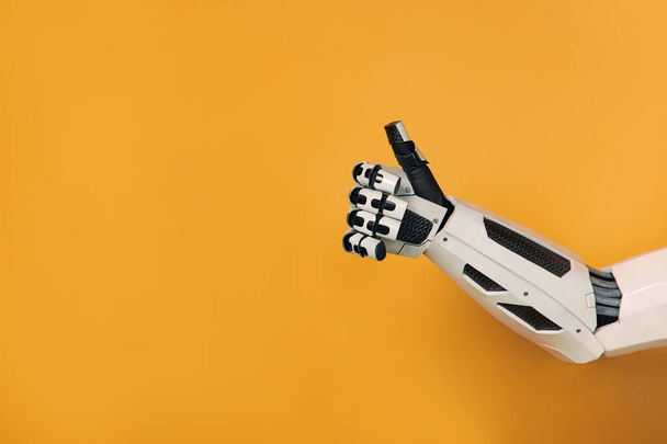 Mão robô mostrando polegares para cima gesto isolado no fundo laranja. Colaboração entre humanos e inteligência artificial. - Foto, Imagem
