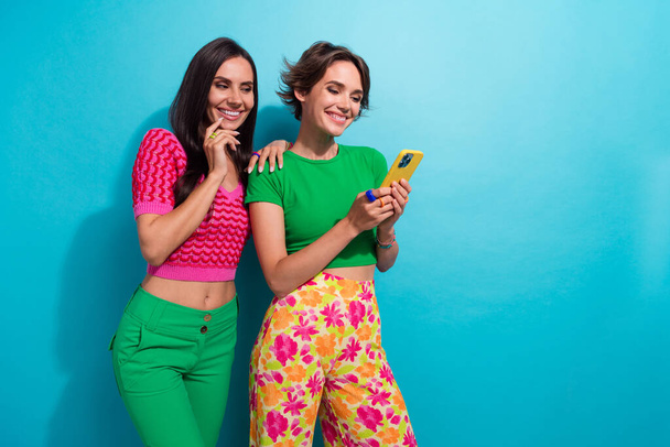 Photo of pretty cute ladies wear colorful clothes communicating modern device empty space isolated blue color background. - Fotografie, Obrázek