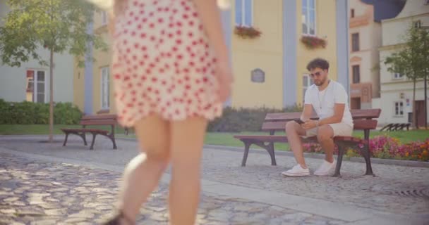 Vista posteriore della donna che saluta il fidanzato seduto sulla panchina nel parco durante le vacanze - Filmati, video