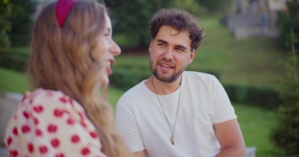 Mujer joven rubia hablando con un amigo varón mientras pasa el tiempo libre en el jardín - Metraje, vídeo