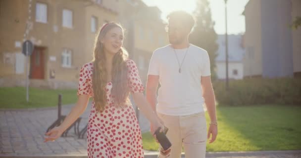 Sorridente donna bionda che parla con il fidanzato mentre cammina sul sentiero nel parco - Filmati, video