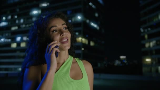 Junge Frau mit zwei Rassen telefoniert nachts in Bürogebäuden. Brasilianisches Model im trendigen Outfit telefoniert mit dem Handy. Stadtmenschen, die Spaß an Gesprächen mit Freunden haben - Filmmaterial, Video