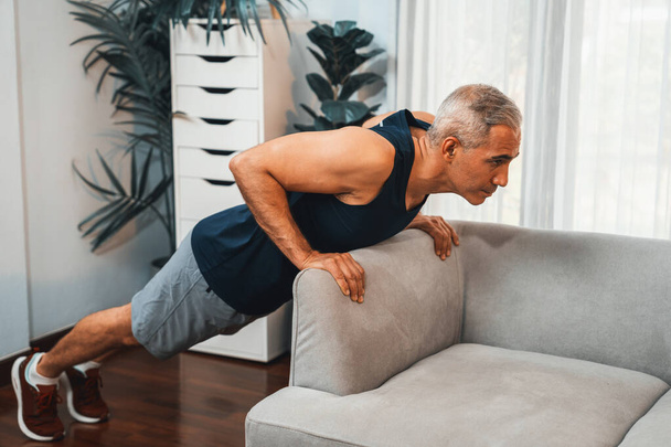 Спортсмен і активний старший чоловік, використовуючи меблі для ефективного націлювання на м'язи з підштовхуванням в домашніх умовах як концепцію здорового способу життя тіла після виходу на пенсію. Розрізати - Фото, зображення