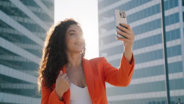 Heureuse blogueuse influenceuse afro-américaine utilisant un téléphone portable, prenant selfie, postant dans les applications de médias sociaux, bavardant avec des amis en ligne sur smartphone debout au centre-ville sous le soleil doré - Séquence, vidéo