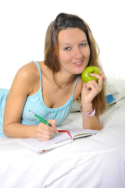 Jovem mulher estudante atraente com maçã em camisola de dormir rel
 - Foto, Imagem