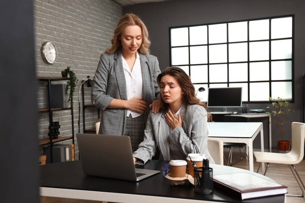 Женщина помогает своему коллеге, у которого приступ паники в офисе - Фото, изображение