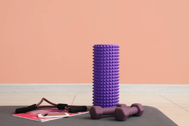 Αθλητικός εξοπλισμός με κινητό τηλέφωνο και περιοδικό για fitness mat κοντά σε ροζ τοίχο στο γυμναστήριο - Φωτογραφία, εικόνα