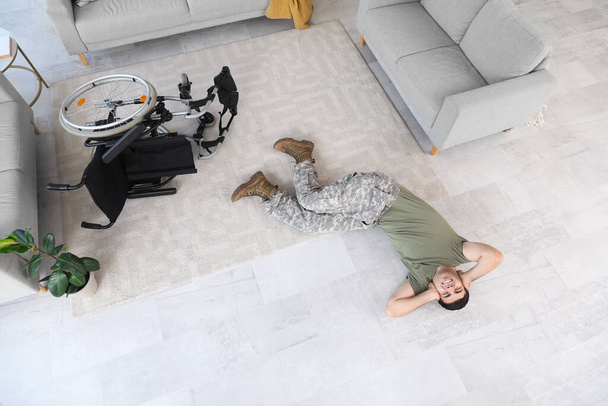 Молодий солдат з ПТСР лежить на підлозі вдома, вид зверху - Фото, зображення